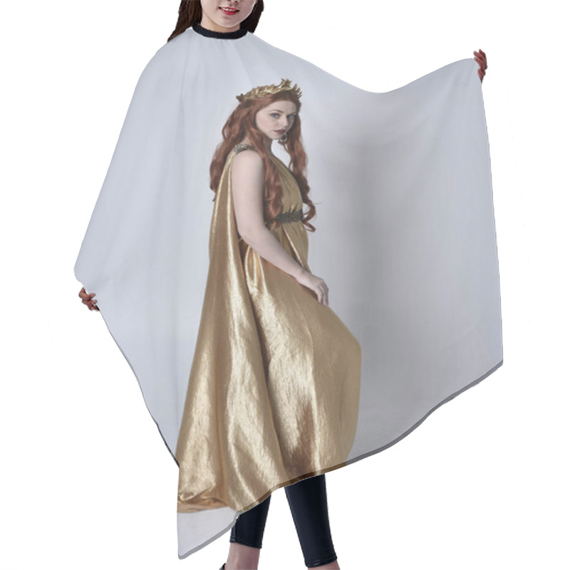 Personality  Full Length Portrait Of Girl With Red Hair Wearing Long Grecian Toga And Golden Wreath. Standing Pose With Back To The Camera,  Isolated Against A Grey Studio Background. Hair Cutting Cape