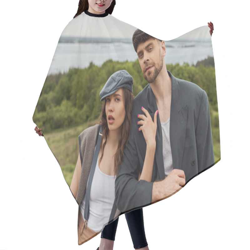 Personality  Fashionable Brunette Woman In Suspenders And Newsboy Cap Hugging Bearded Boyfriend In Jacket And Looking At Camera Together With Blurred Landscape At Background, Fashionable Couple In Countryside Hair Cutting Cape