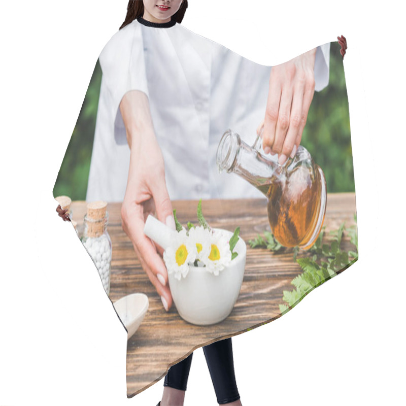 Personality  Cropped View Of Woman Holding Jug With Oil Near Mortar With Flowers And Green Leaves On Wooden Table  Hair Cutting Cape