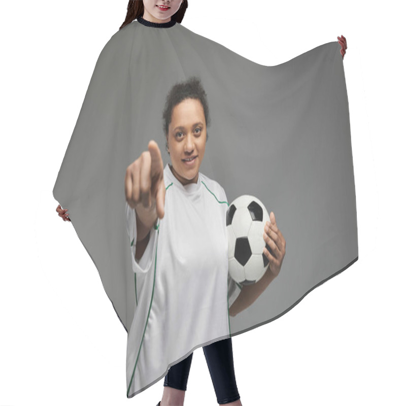 Personality  A Woman In A White Jersey Holds A Soccer Ball And Points Her Finger Towards The Camera. Hair Cutting Cape