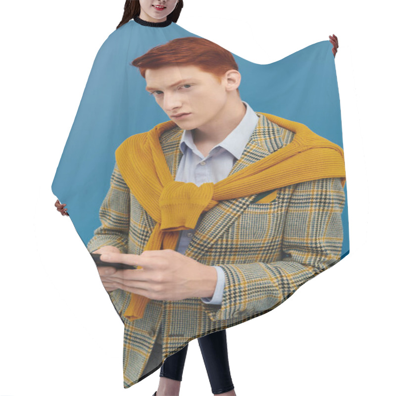 Personality  A Young Man With Red Hair Confidently Poses In A Stylish Layered Winter Outfit Against A Blue Background. Hair Cutting Cape