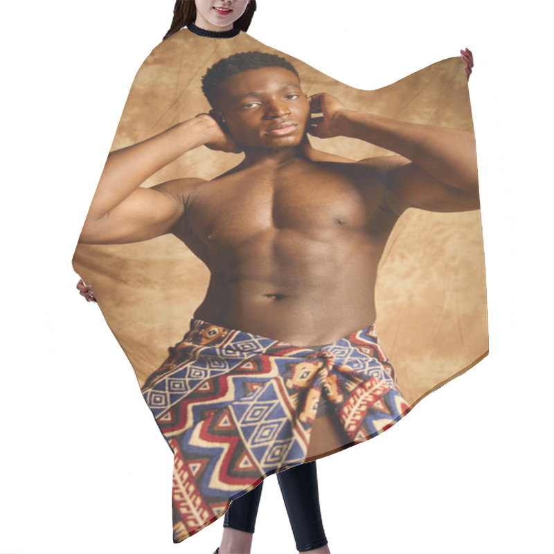 Personality  A Young Handsome African American Man Poses Confidently, Showcasing His Physique. Wearing A Patterned Wrap, He Embodies Strength And Culture Against A Warm, Artistic Backdrop. Hair Cutting Cape