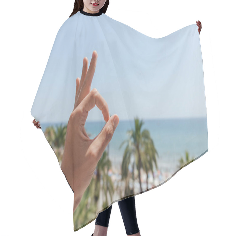 Personality  Cropped View Of Man Showing Okay Gesture With Palm Trees And Sea At Background In Catalonia, Spain  Hair Cutting Cape