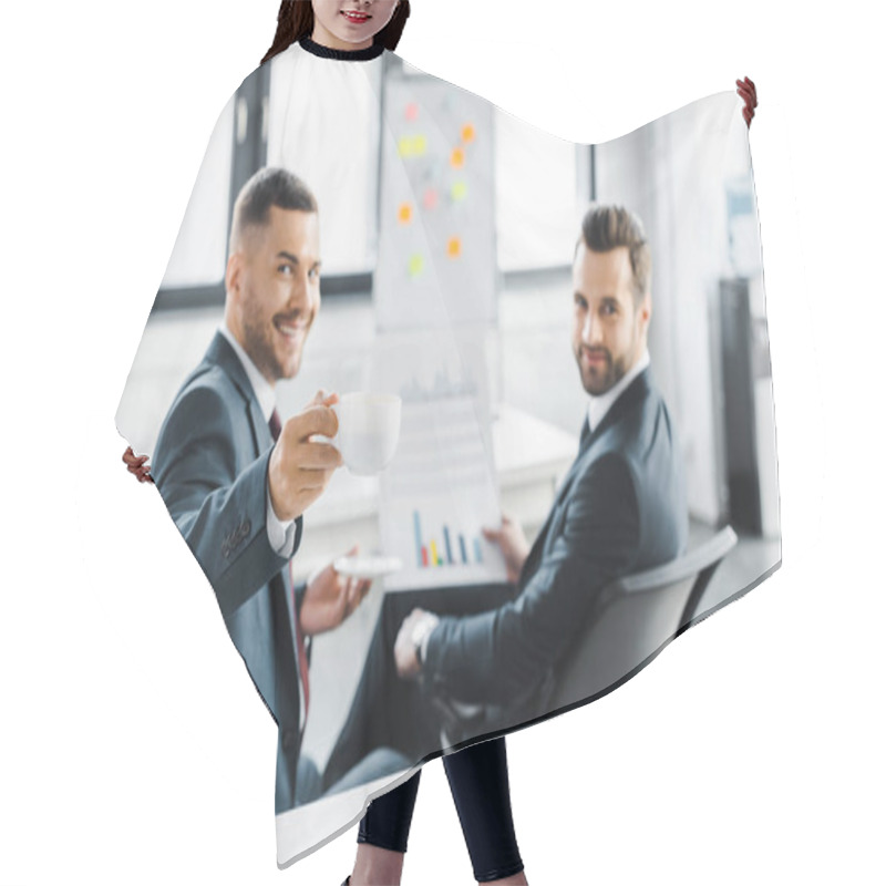 Personality  Selective Focus Of Cup With Drink In Hand Of Cheerful Businessman Near Coworker Holding Paper With Graphs Hair Cutting Cape