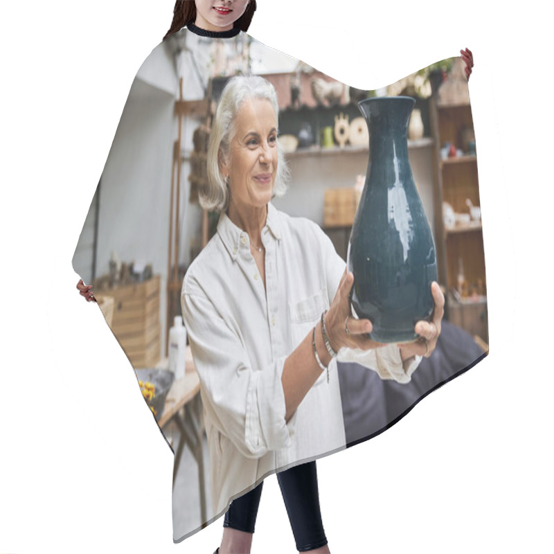 Personality  A Joyful Mature Woman Presents A Striking Pottery Vase Surrounded By Lush Greenery. Hair Cutting Cape