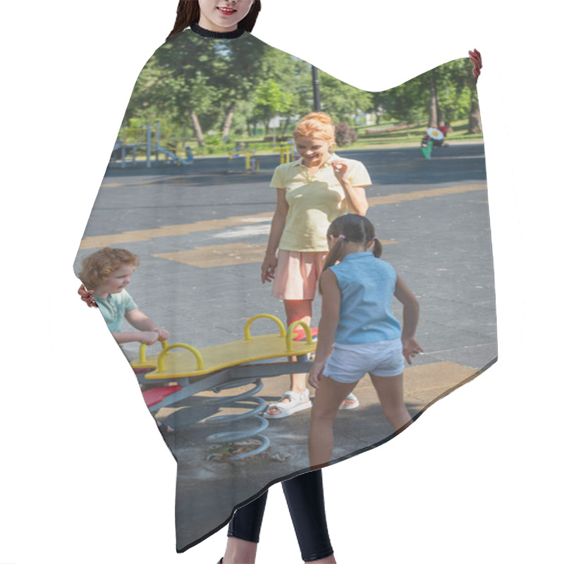 Personality  Pleased Woman Standing Near Children And Seesaw In Park Hair Cutting Cape