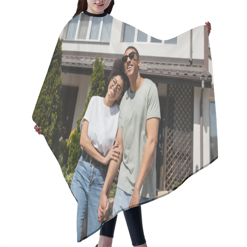 Personality  Smiling African American Woman In Eyeglasses Hugging Boyfriend Near New House At Background Hair Cutting Cape