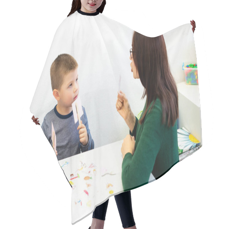 Personality  Children Speech Therapy Concept. Preschooler Practicing Correct Pronunciation With A Female Speech Therapist. Hair Cutting Cape