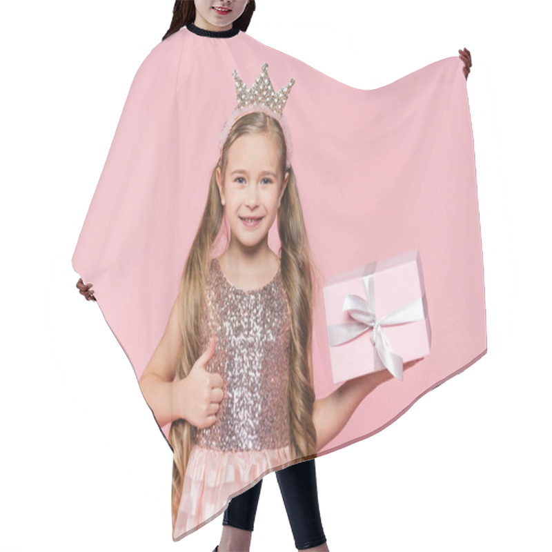 Personality  Joyful Little Girl In Crown Holding Wrapped Present Showing Thumb Up Isolated On Pink  Hair Cutting Cape