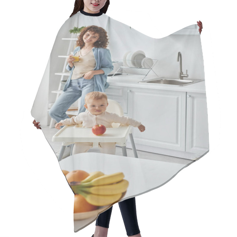 Personality  Joyful Woman With Glass Of Orange Juice Near Toddler Kid In Baby Chair And Ripe Fruits In Kitchen Hair Cutting Cape