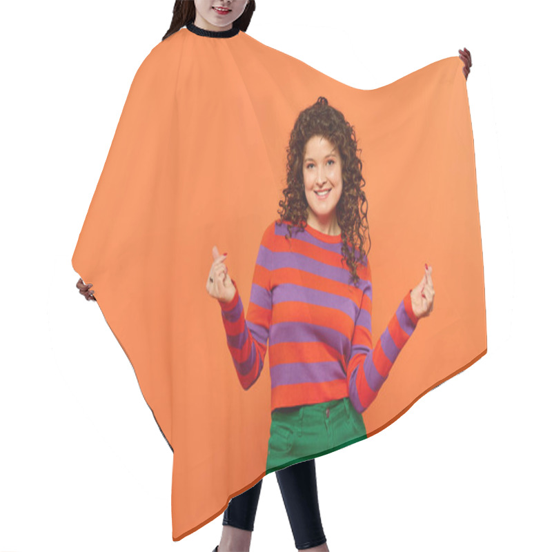 Personality  A Young Woman With Curly Hair Smiles Brightly While Posing In Vibrant Attire Against A Bright Orange Background. Hair Cutting Cape