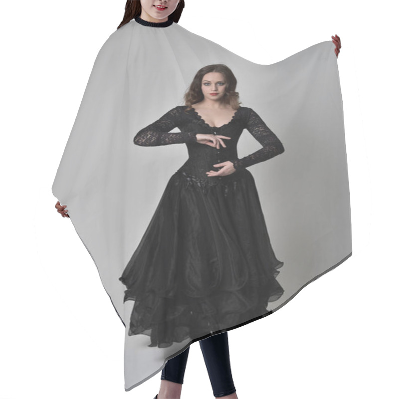 Personality  Full Length Portrait Of Brunette Girl Wearing Long Black Lace Gown Wit Corset. Standing Pose, Isolated On Grey Studio Background. Hair Cutting Cape