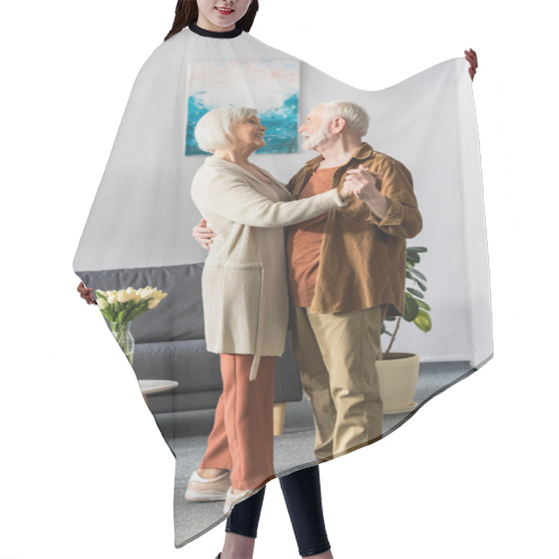 Personality  Happy Senior Couple Dancing While Looking At Each Other Near Table With Tulips Hair Cutting Cape