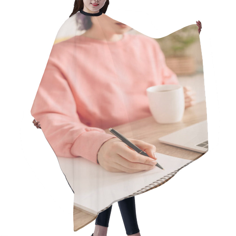 Personality  Cropped View Of Freelancer Holding Cup Of Tea And Writing In Notebook At Table Hair Cutting Cape