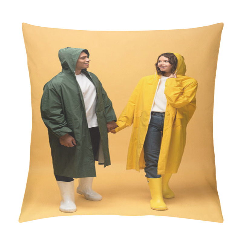 Personality  Smiling Interracial Couple In Raincoats And Rubber Boots Holding Hands On Yellow Background Pillow Covers