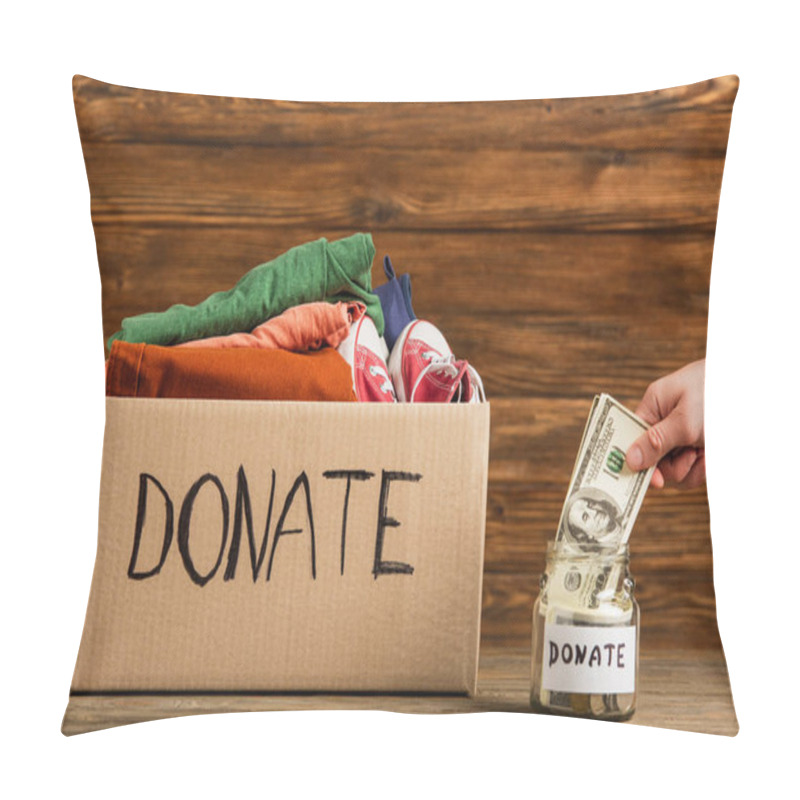 Personality  Cropped View Of Man Putting Money In Jar Near Cardboard Box With Donate Lettering And Clothes On Wooden Background, Charity Concept Pillow Covers