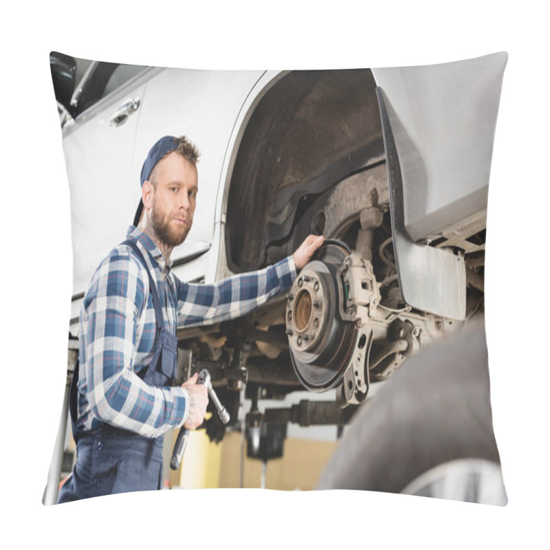 Personality  Technician Looking At Camera While Standing Near Lifted Automobile With Wrench On Blurred Foreground Pillow Covers