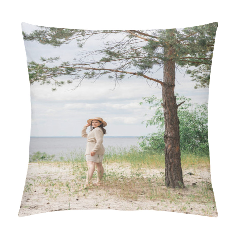 Personality  Full Length Of Smiling Young Woman Adjusting Straw Hat And Standing In Woods Near Lake Pillow Covers