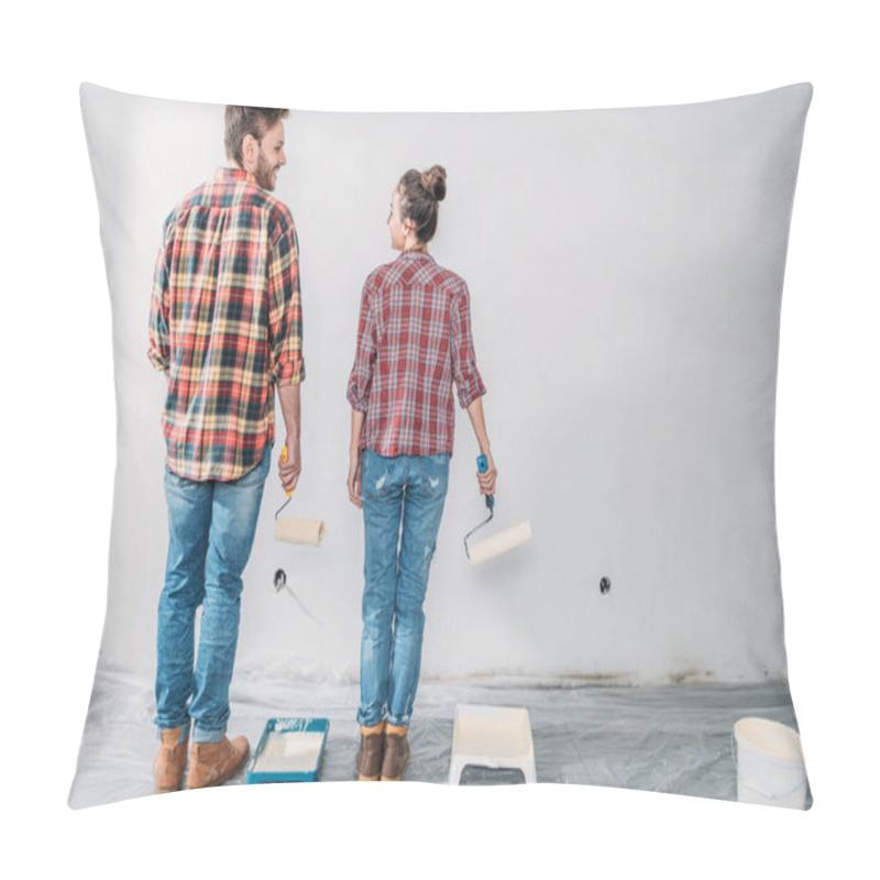 Personality  Back View Of Young Couple Holding Paint Rollers And Smiling Each Other During Renovation Pillow Covers