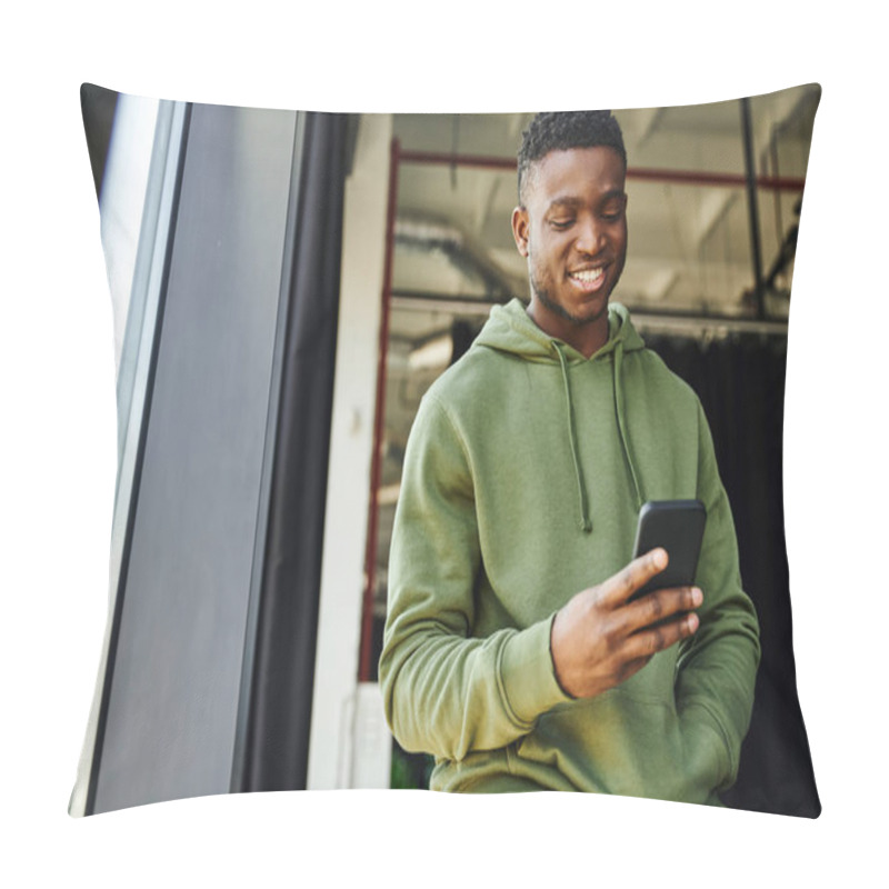 Personality  Young And Cheerful African American Man Holding Hand In Pocket Of Green Hoodie And Browsing Internet On Mobile Phone In Modern Office, Successful Businessman, Positive Emotion  Pillow Covers