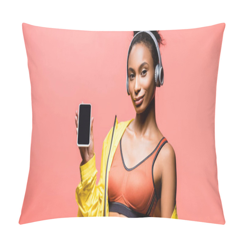 Personality  Panoramic Shot Of Beautiful African American Sportswoman In Headphones Looking At Camera And Presenting Smartphone With Blank Screen Isolated On Coral Pillow Covers