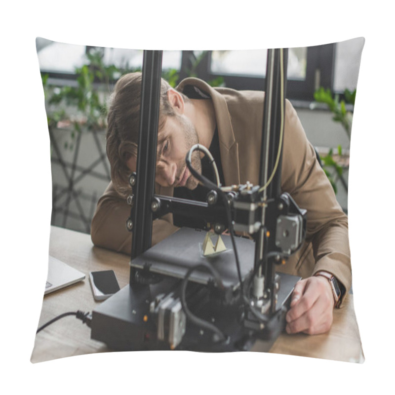 Personality  Concentrated Young Designer Looking At 3D Printer Producing Plastic Figure Near Laptop And Cellphone In Modern Office Pillow Covers