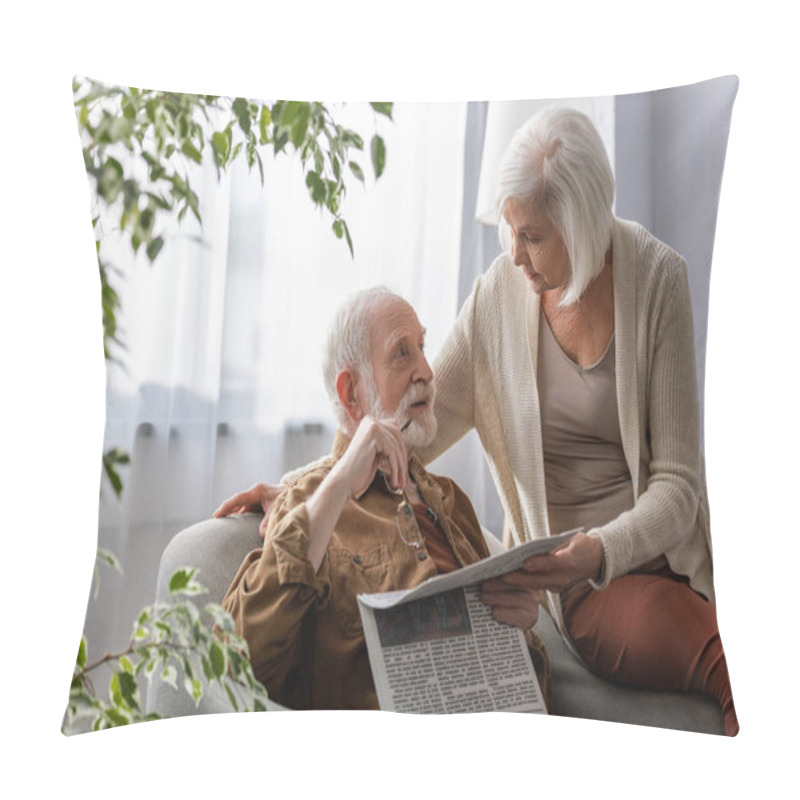 Personality  Senior Woman Talking To Husband Holding Newspaper And Eyeglasses While Sitting In Armchair Pillow Covers