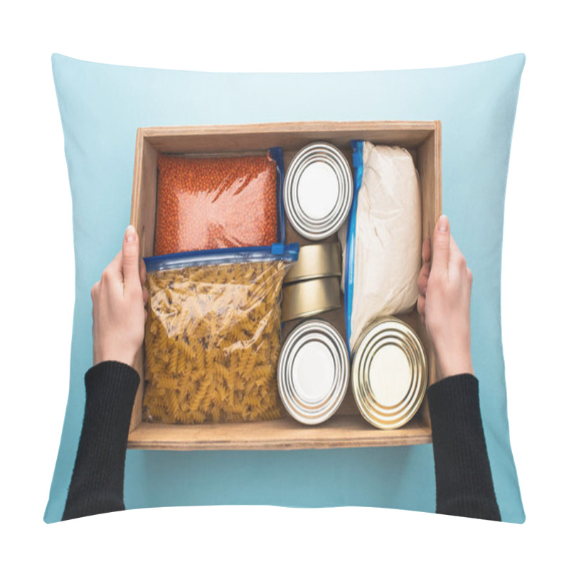 Personality  Cropped View Of Woman Holding Wooden Box With Cans And Groats In Zipper Bags On Blue Background Pillow Covers