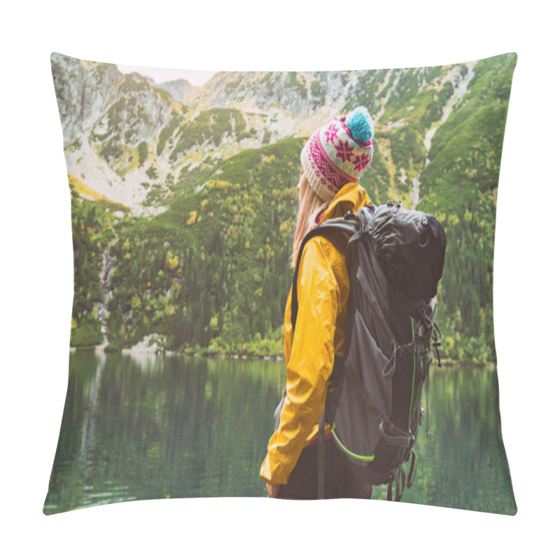 Personality  Young Blond Hair Woman With Big Camping Rucksack Wearing Yellow Raincoat Jacket, Purple And Blue Cap Looking On Mountains And Lake. Copy Space, Rear View Background. Pillow Covers