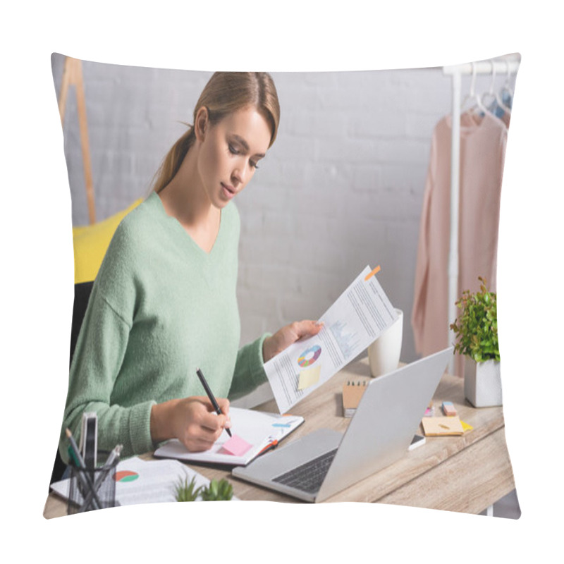 Personality  Freelancer Writing On Notebook While Holding Document With Charts Near Laptop On Table  Pillow Covers