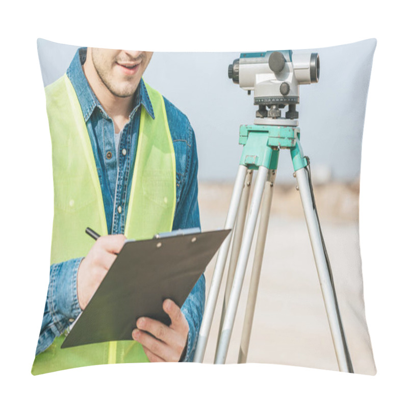 Personality  Cropped Shot Of Smiling Surveyor Writing On Clipboard Beside Digital Level  Pillow Covers