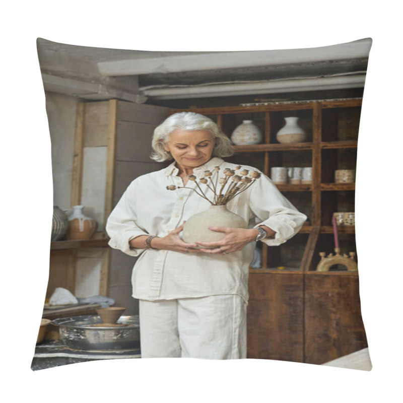 Personality  The Mature Woman Holds A Unique Vase Filled With Dried Flowers, Smiling Softly In Her Studio. Pillow Covers