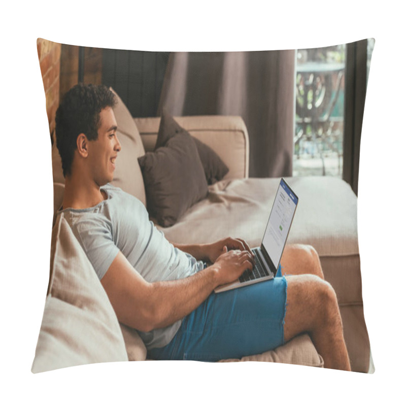 Personality  KYIV, UKRAINE - APRIL 27, 2020: Smiling Mixed Race Man Using Laptop With Facebook On Screen During Self Isolation Pillow Covers