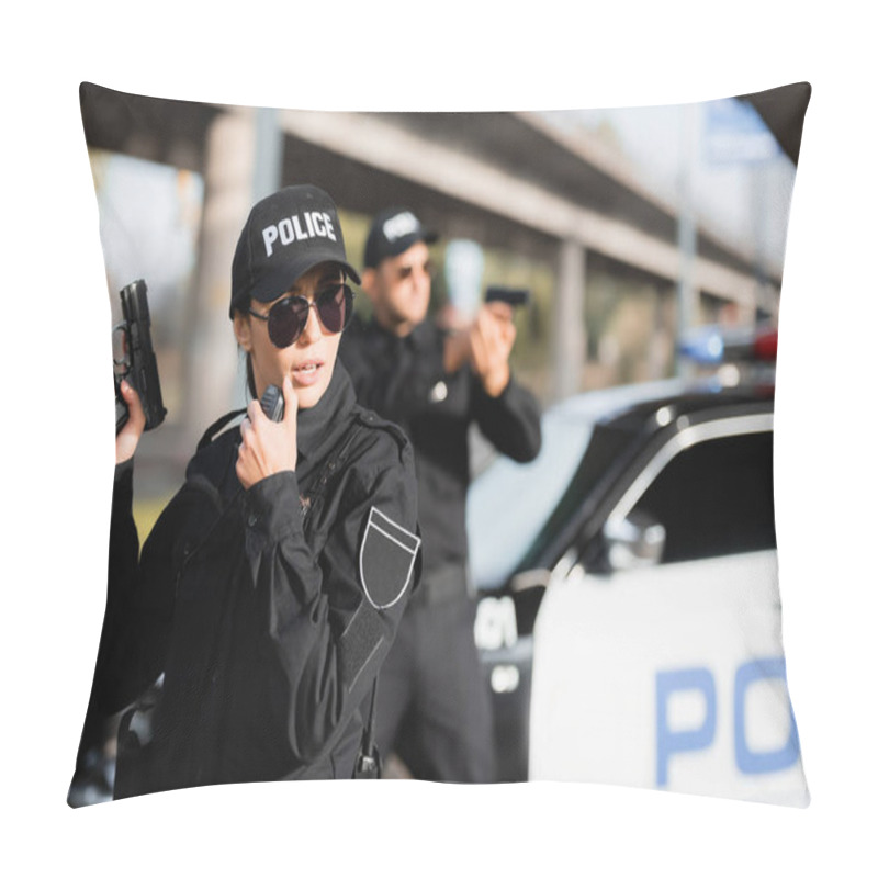 Personality  Policewoman In Sunglasses Holding Gun And Using Walkie Talkie Near Colleague And Car On Blurred Background  Pillow Covers