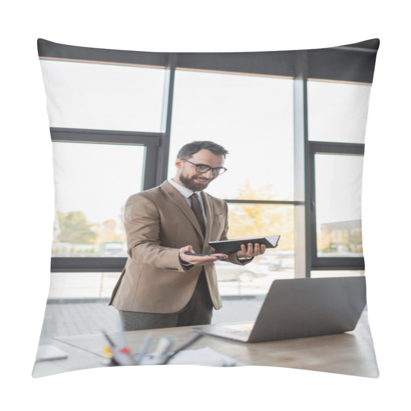 Personality  Smiling Charismatic Businessman In Stylish Business Attire Holding Notebook And Pointing With Hand At Laptop Near Blurred Smartphone And Stationery While Having Video Conference In Modern Office Pillow Covers