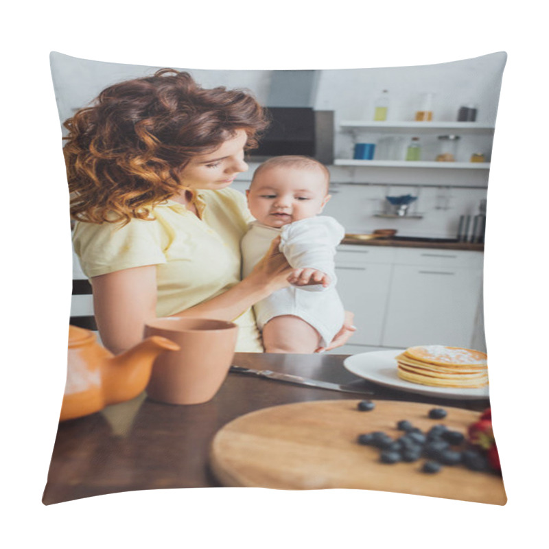 Personality  Selective Focus Of Curly Mother Holding Infant Boy Pointing With Hand At Table Served With Breakfast Pillow Covers