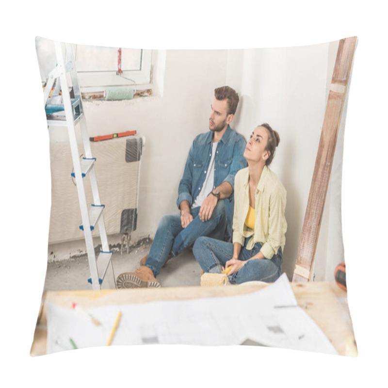 Personality  Thoughtful Young Couple Sitting In Floor And Looking Away During House Repair Pillow Covers