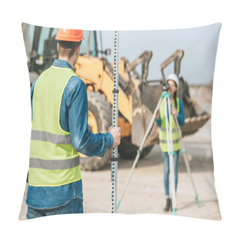 Personality  Selective Focus Of Surveyors Using Ruler And Digital Level With Bulldozer At Background Pillow Covers