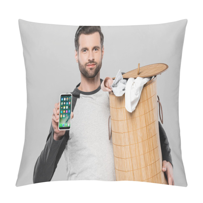 Personality  KYIV, UKRAINE - MARCH 23, 2020: Handsome Man Holding Laundry Basket And Iphone Isolated On Grey Pillow Covers