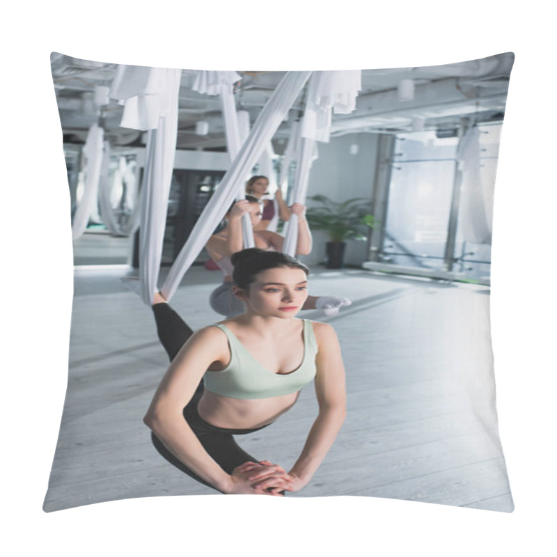 Personality  Pretty Young Woman Stretching Leg With Aerial Yoga Strap Near Group On Blurred Background Pillow Covers