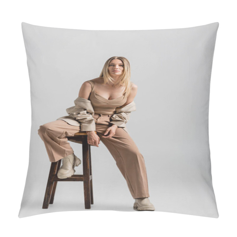 Personality  Young Blonde Woman In Beige Formal Suit Sitting On Chair Posing On Grey Backdrop, Fashion Concept Pillow Covers