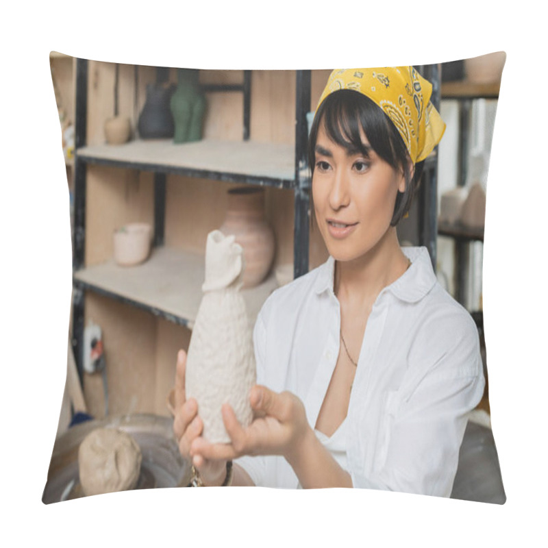 Personality  Smiling Young Asian Artist In Headscarf And Workwear Holding And Looking At Clay Sculpture While Working In Ceramic Workshop, Artisan In Pottery Studio Focusing On Creation Pillow Covers