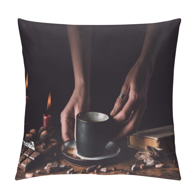 Personality  Cropped Shot Of Woman Holding Cup Of Coffee At Wooden Table With Chocolate, Truffles, Coffee Grains, Candles And Book On Black Background  Pillow Covers