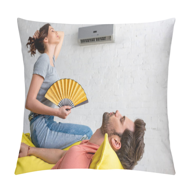 Personality  Young Woman With Hand Fan Sitting On Yellow Sofa Under Air Conditioner Near Lying Man  Pillow Covers