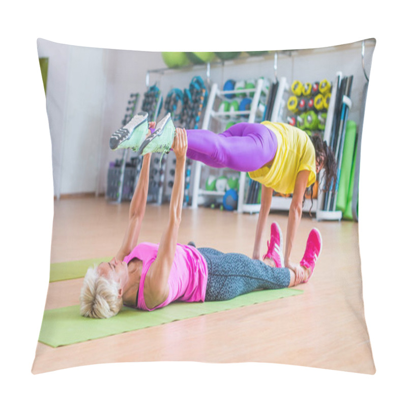 Personality  Two Female Fitness Models Doing Yoga Exercises, One Lying On Floor  Mat Holding Legs Of Another Above Her In A Sports Center Pillow Covers