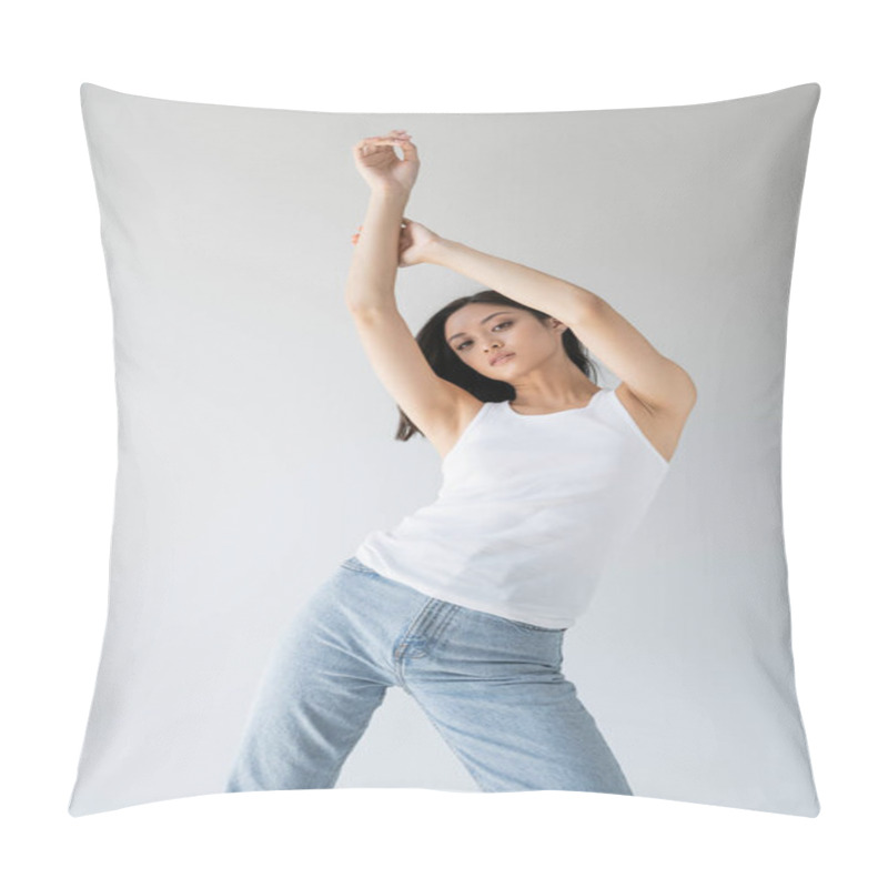 Personality  Slender Asian Woman In White Tank Top And Blue Jeans Posing With Raised Hands Isolated On Grey Pillow Covers