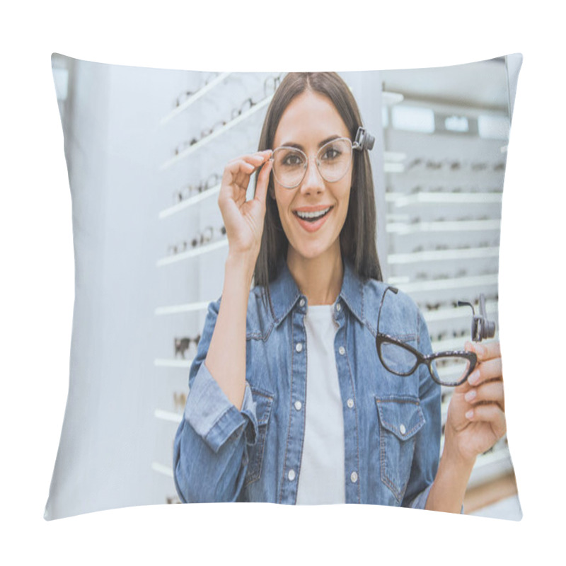 Personality  Cheerful Young Woman Choosing Eyeglasses And Looking At Camera In Ophthalmic Shop Pillow Covers