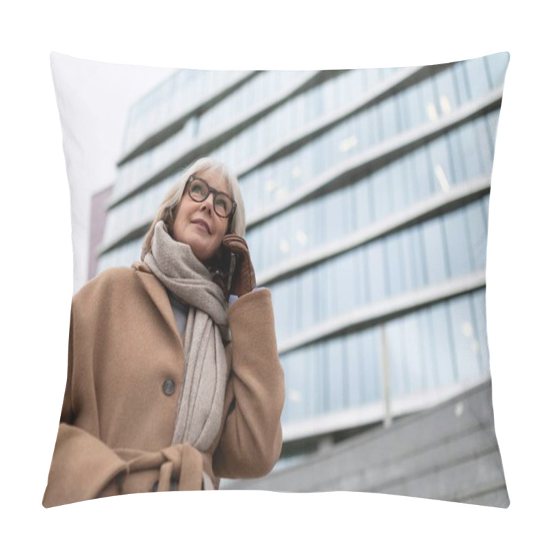 Personality  A Woman With Gray Hair And Glasses Is Engaged In A Phone Conversation. She Wears A Warm Coat And Scarf, Ready For The Cold Weather Outside A Contemporary Building. Pillow Covers