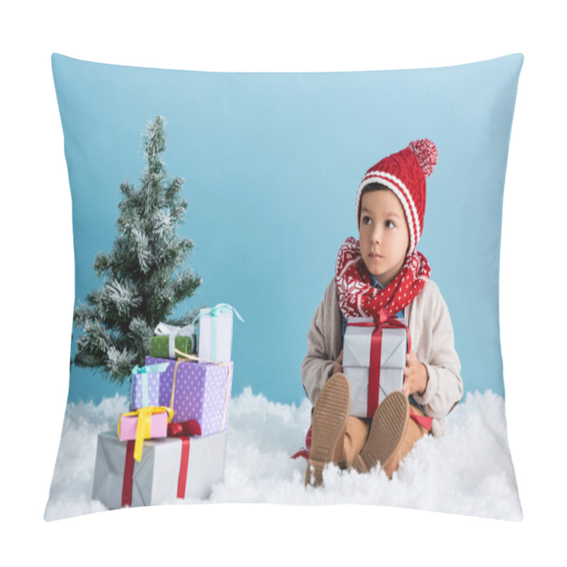 Personality  Boy In Hat And Winter Outfit Sitting On Snow Near Presents And Christmas Trees Isolated On Blue Pillow Covers