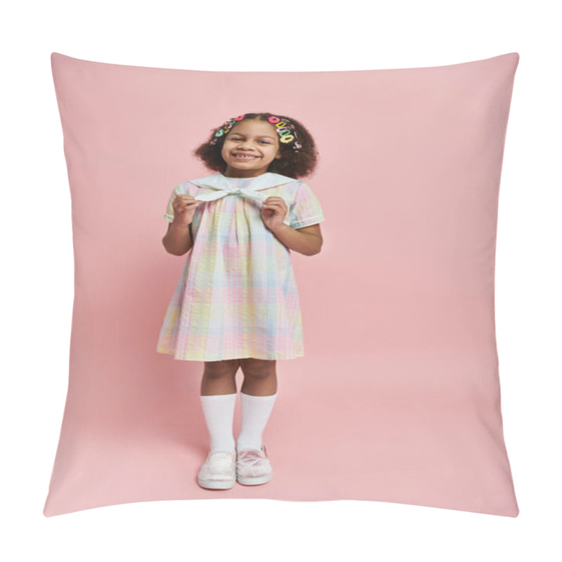 Personality  A Cute African American Girl With Hair Clips Smiles Brightly While Standing In A Rainbow Checkered Dress Against A Pink Background. Pillow Covers